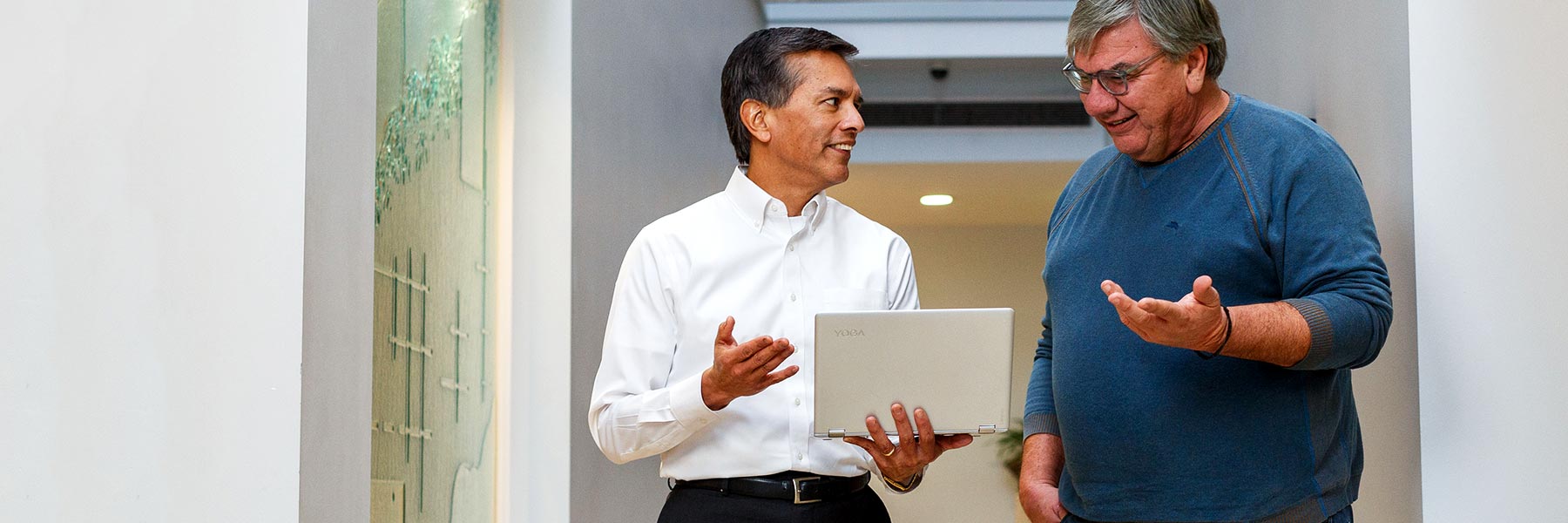 Two men look at a laptop computer and talk.