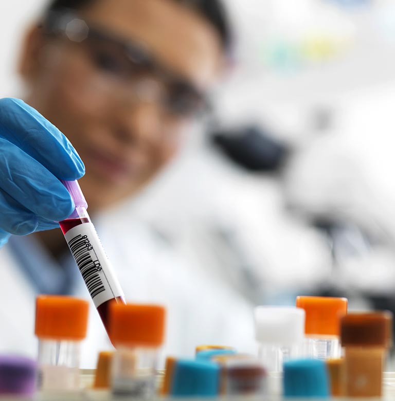 A laboratory worker holds a vial of blood.