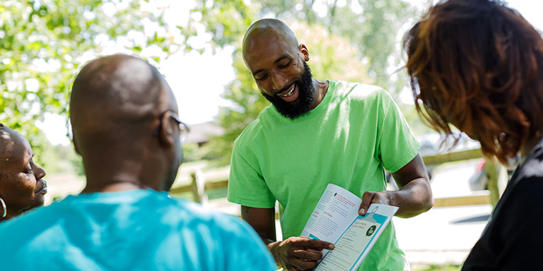 A man shows a booklet to three people.